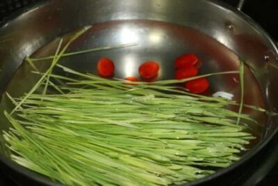 Revitalizing Wheatgrass Rasam: A Tangy South Indian Soup - Plattershare - Recipes, food stories and food lovers Wheatgrass Rasam in a pot with fresh wheatgrass and tomatoes, ready to be cooked into a tangy South.
