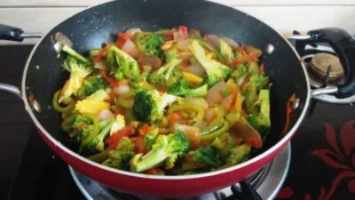 Vibrant Veggie Farfalle: A Delightful and Easy Pasta Recipe - Plattershare - Recipes, food stories and food lovers Colorful vegetable pasta stir-fry with broccoli, bell peppers, and tomatoes in a black skillet.
