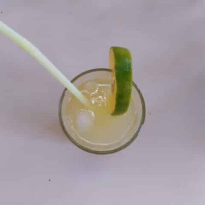 Refreshing Indo-Burmese Lemonade: A Sweet and Tangy Escape - Plattershare - Recipes, food stories and food lovers Burmese Lemonade in a glass with a lime wedge and straw, showcasing a sweet and tangy beverage.