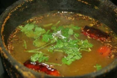 Revitalizing Wheatgrass Rasam: A Tangy South Indian Soup - Plattershare - Recipes, food stories and food lovers Wheatgrass Rasam in a pot with fresh herbs and spices, showcasing a tangy South Indian soup.