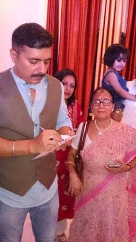 Food Fiesta With Living Foodz Celebrity - Plattershare - Recipes, food stories and food lovers A man signing autographs at a family celebration with women and children in the background.