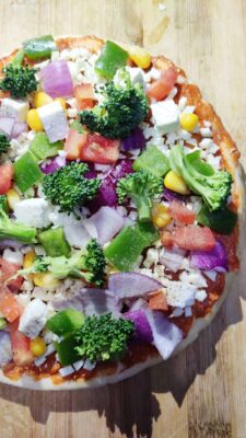 Loaded Vegetarian Pizza: A Crispy, Cheesy Delight - Plattershare - Recipes, food stories and food lovers Colorful vegetable pizza with broccoli, corn, onions, and peppers on a wooden surface.