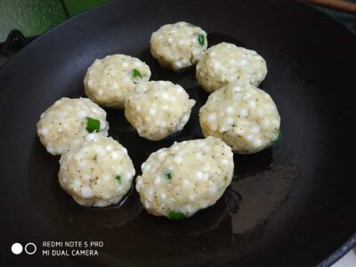 Healthy Sago Tikki (Sabudana Tikki): A Quick & Nutritious Snack or Light Meal - Plattershare - Recipes, food stories and food lovers Soft spongy idli dumplings cooking on a black skillet, garnished with green chilies, ready to serve.