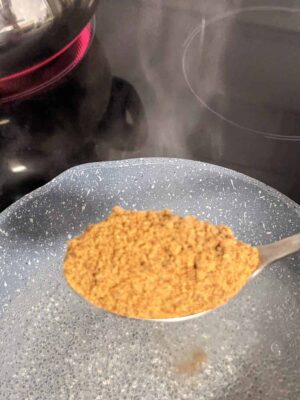 Quick & Easy Puffed Rice Pongal: A Healthy Indian Dessert - Plattershare - Recipes, food stories and food lovers Brown sugar being added to a hot pan or container, with steam rising.