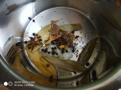 Authentic Bengali Chicken Rezala: A Rich and Flavorful Mughlai Dish - Plattershare - Recipes, food stories and food lovers Spices in a stainless steel cooker including bay leaves, cinnamon, star anise, cardamom, and peppercorns.