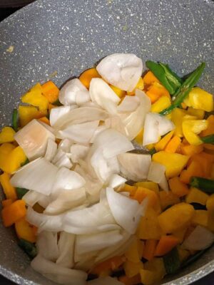 Vibrant Tricolor Pasta with Crispy Fried Paneer - Plattershare - Recipes, food stories and food lovers Colorful chopped vegetables in a non-stick pan ready for cooking.