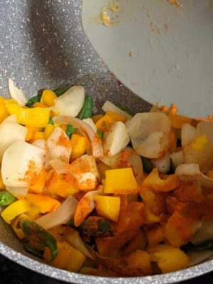 Vibrant Tricolor Pasta with Crispy Fried Paneer - Plattershare - Recipes, food stories and food lovers Colorful vegetable stir-fry cooking in a non-stick pan with spices and fresh ingredients for a healthy meal.
