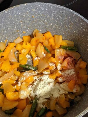 Vibrant Tricolor Pasta with Crispy Fried Paneer - Plattershare - Recipes, food stories and food lovers Colorful chopped vegetables cooking in a non-stick pan with spices and herbs.