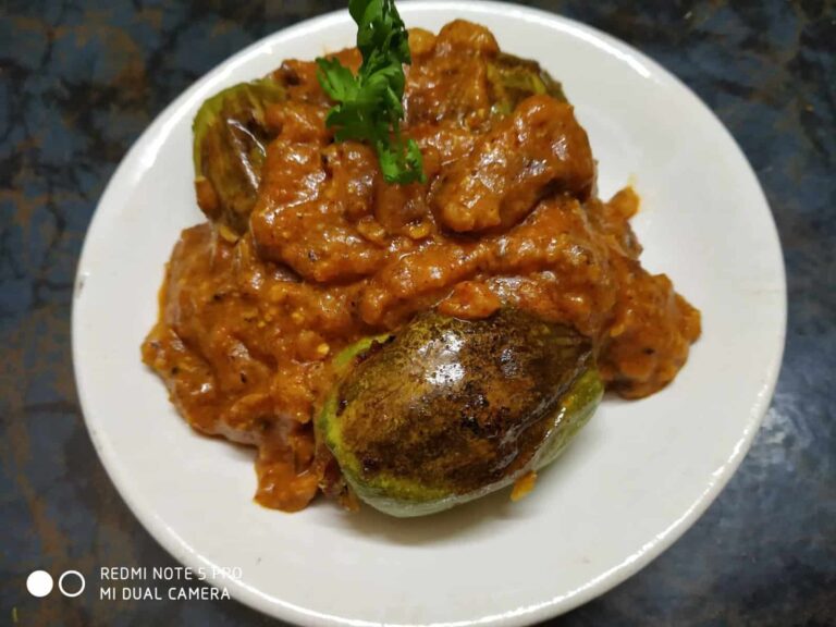 Spiced Stuffed Pointed Gourd: A Flavorful Bengali Vegetarian Recipe - Plattershare - Recipes, food stories and food lovers Spicy eggplant and tomato curry served on a white plate with fresh cilantro garnish.