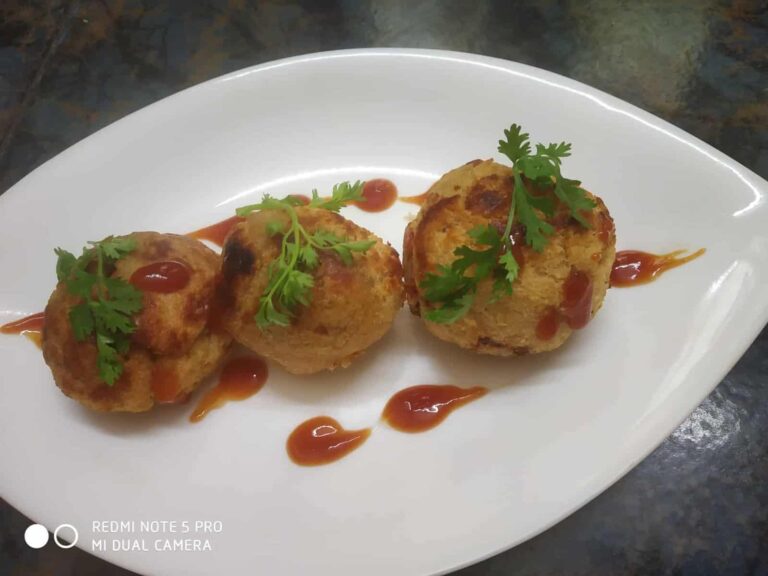 Savory Atta Bread Appam: A Delicious Indian Bread Snack - Plattershare - Recipes, food stories and food lovers Crispy paneer balls garnished with cilantro and drizzled with spicy sauce on a white platter.