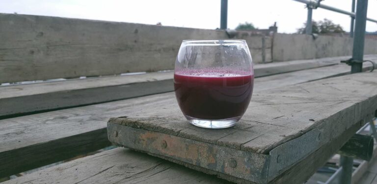 Energizing Beetroot, Apple, Orange & Gooseberry Juice Recipe - Plattershare - Recipes, food stories and food lovers Fresh beetroot juice served in a glass on a rustic wooden table, perfect for healthy food lovers.