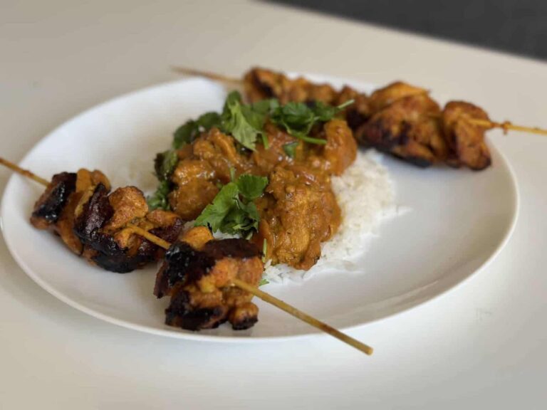 Dhaba-Style Chicken Curry with Oats Masala: A Weekend Recipe - Plattershare - Recipes, food stories and food lovers Skewered chicken kebabs with spicy curry and rice garnished with fresh cilantro on a white plate.