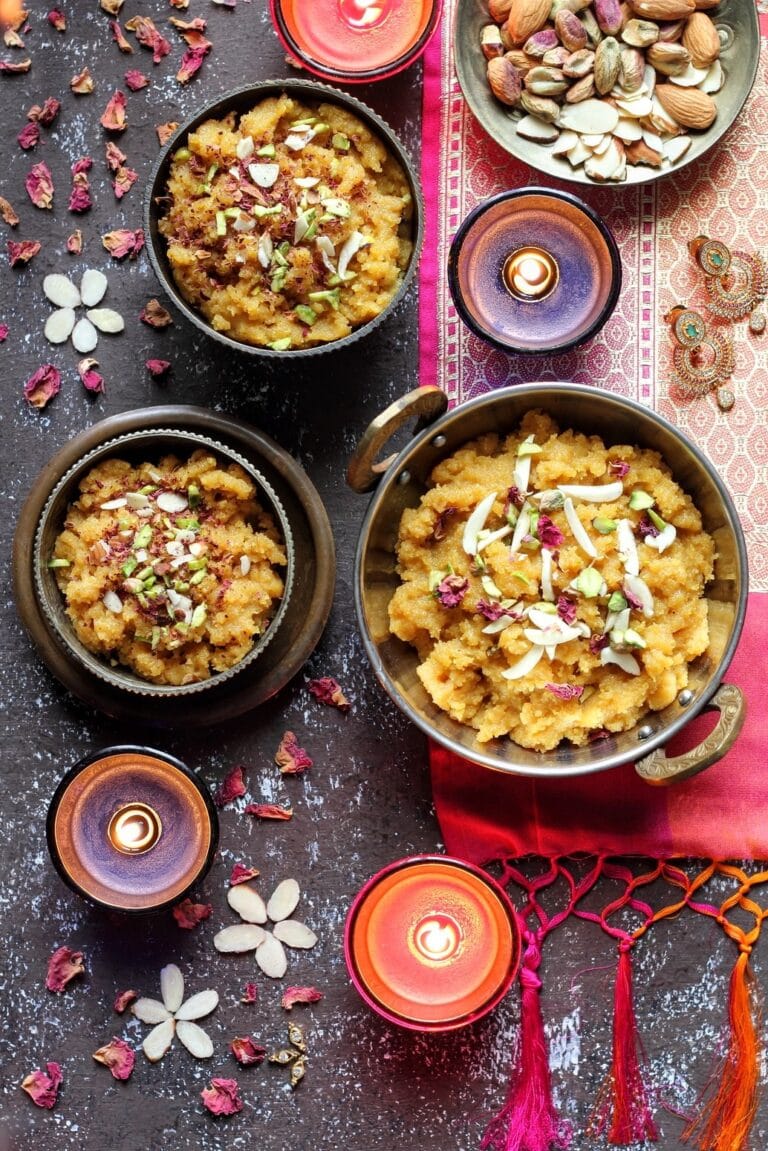 Moong Dal Halwa - Plattershare - Recipes, food stories and food lovers Colorful Indian sweets with almonds and rose petals on a dark surface, festive and inviting, perfect for celebrations.
