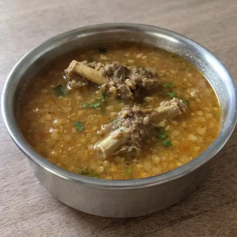 Comforting Lamb Bone & Red Lentil Soup (Yelumbu Paruppu Soup) - Plattershare - Recipes, food stories and food lovers Savory mutton stew in stainless steel bowl with herbs and spices.