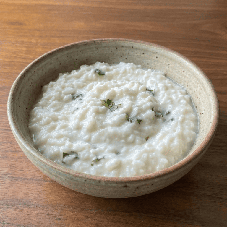 Simple Curd Rice (Light, Home-Style) - Plattershare - Recipes, food stories and food lovers Creamy raita with herbs in a rustic bowl on wooden surface.