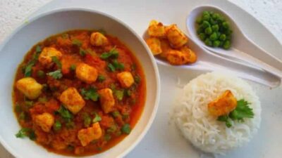 A flavorful Indian curry with green peas, paneer, and spices served with rice and side snacks.