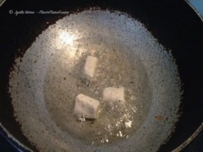 Chili garlic paneer being cooked in a pan, showcasing the fiery Indo-Chinese flavor profile of this.