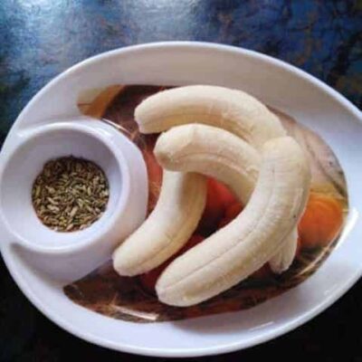 Bengali banana rolls served with spices and herbs on a white plate.