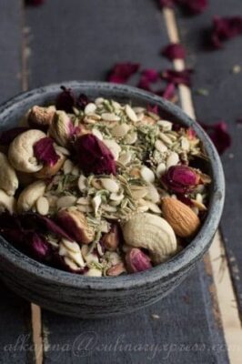 Thandai Masala spice blend in a bowl with nuts and dried rose petals.
