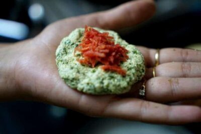 Crispy coriander paneer balls with red pepper sauce on a hand.
