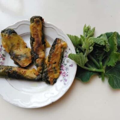 Bengali Pumpkin Leaf Rolls with Spiced Paneer on a white plate.