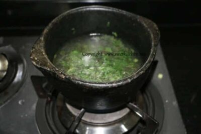 Congee made with black rice, barley, and flax seeds in a pot on stove.