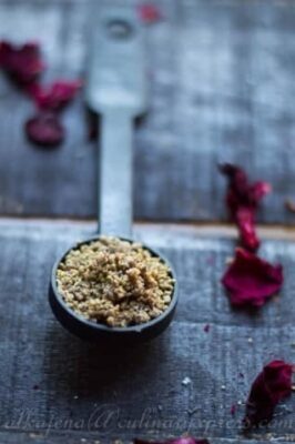 Thandai Masala spice blend in a spoon for refreshing Indian drinks.