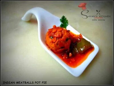Indian Chicken Meatball Pot Pie in a white spoon with spicy gravy and fresh cilantro garnish.
