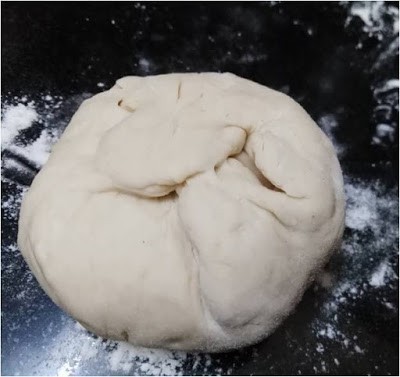 Dough ball for Spicy Schezwan Paratha on a black surface.