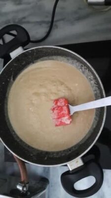 Cooking coconut kalakand mixture in a pan for cheesecake.