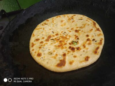 Golden brown stuffed paratha cooking in a skillet, crispy and delicious Indian bread.