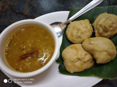 Hot and crispy vada with spicy sambar dip, served on a banana leaf for authentic flavor. Perfect South Indian breakfast.