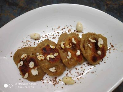 Golden fried snacks garnished with nuts and spices on a white plate, delicious Indian street food or appetizer.
