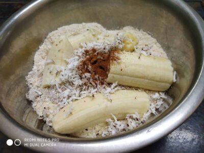 Creamy peeled bananas with shredded coconut and spices in a stainless steel bowl.