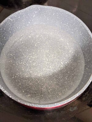 Boiling water in a silver kettle with condensation on the surface, hot and steamy for cooking or tea.