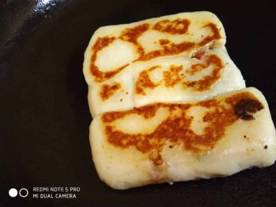 Golden brown grilled bread stuffed with cheese on a black skillet.
