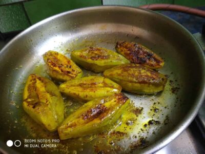 Golden fried plantains sizzling in a pan with butter and seasoning.