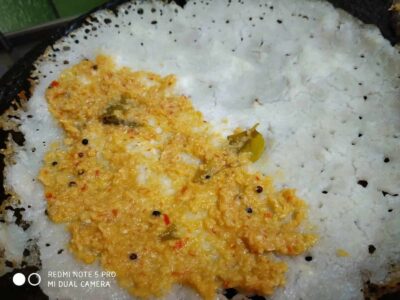 Spicy mustard seed and chili tempering on white rice in a traditional Indian kitchen skillet.