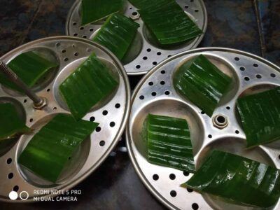 Fresh banana leaf parcels in steamer trays, ready for steaming traditional Indian dishes.
