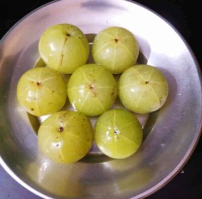 Fresh green Indian gooseberries, also known as amla, in a stainless steel bowl for health benefits.