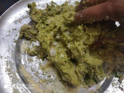 Creamy mashed potatoes with green herbs and a hint of spice, served on a stainless steel plate.