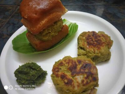 Steamed kachori with green chutney and crispy fried vada on a white plate.