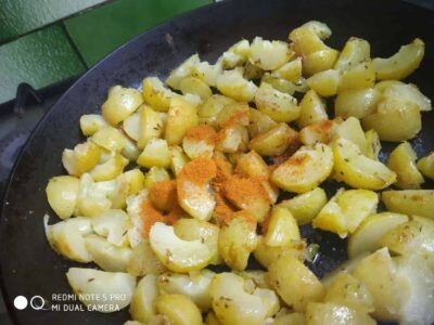Softened cooked potatoes with turmeric and spices in a pan, ready for recipe preparation.