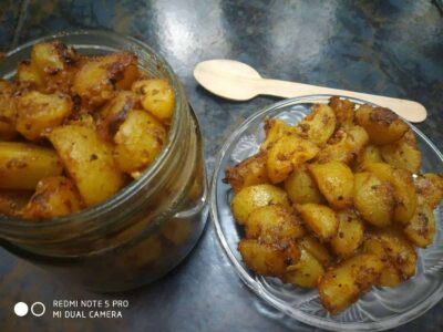 Crispy spiced boiled potatoes served in glass jars and on a plate, garnished with authentic Indian spices, traditional comfort food.
