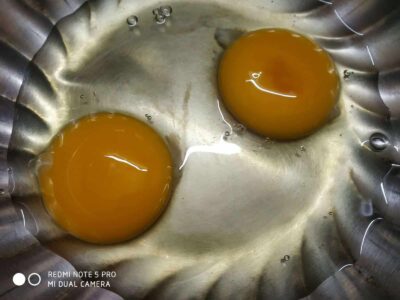 Fresh eggs cracked in a metal container, ready for cooking or baking.