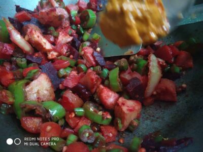 Fresh mixed vegetable stir-fry with tomatoes, green beans, eggplants, and spices, cooked in a skillet.