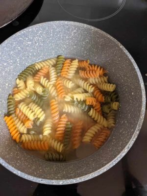 Colorful tricolor fusilli pasta boiling in water.
