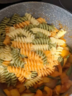 Colorful tri-color fusilli pasta in a pan, ready to be cooked or served.