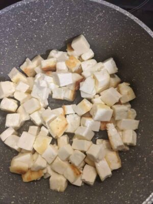 Diced paneer cooking in a non-stick pan.