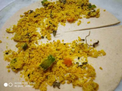 Spiced up idli with seasoned chickpea flour topping and green chilies. Traditional South Indian snack with flavorful ingredients.